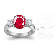 Three Stone Ruby Engagement Ring: Platinum ruby diamond ring set with center oval ruby and side diamond rounds.